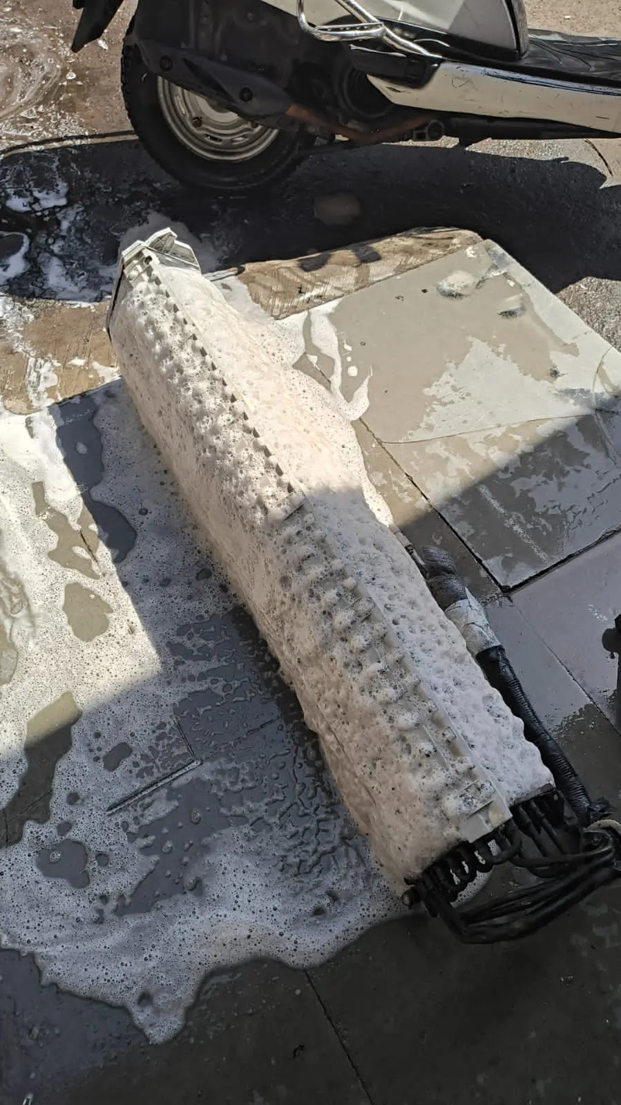 Technician foam-cleaning an evaporator coil during a preventive maintenance visit